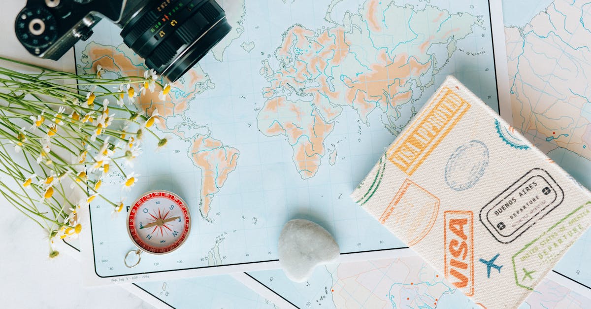 Flat lay of travel essentials - maps, camera, compass, and travel journal for planning adventures.