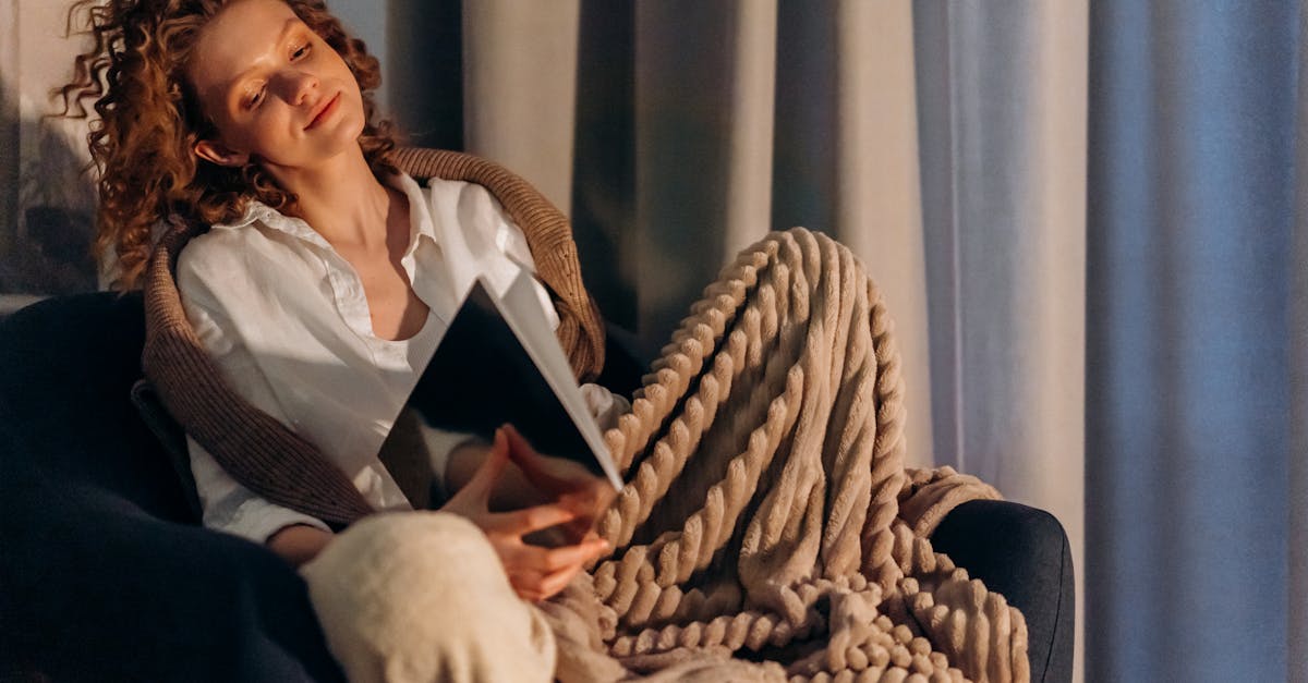 A serene woman in casual attire rests on a luxurious leather sofa in a dimly lit room.