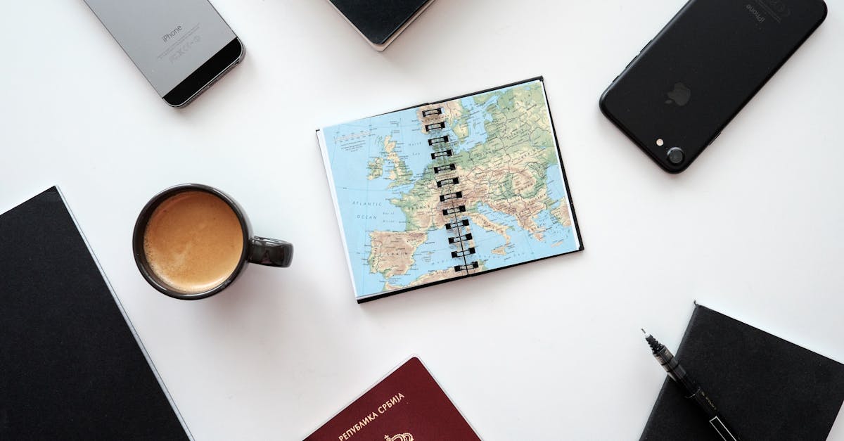 Flat lay of travel essentials with map, passport, and devices on a white surface.