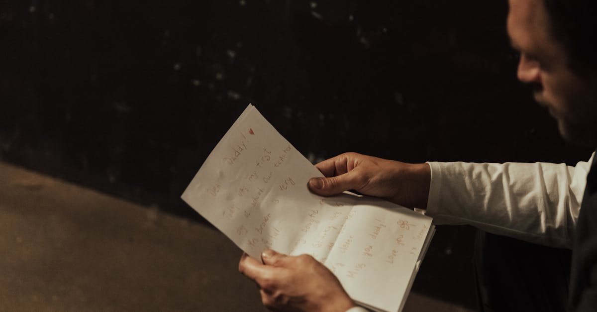 A man sitting indoors, reading a heartfelt handwritten letter.