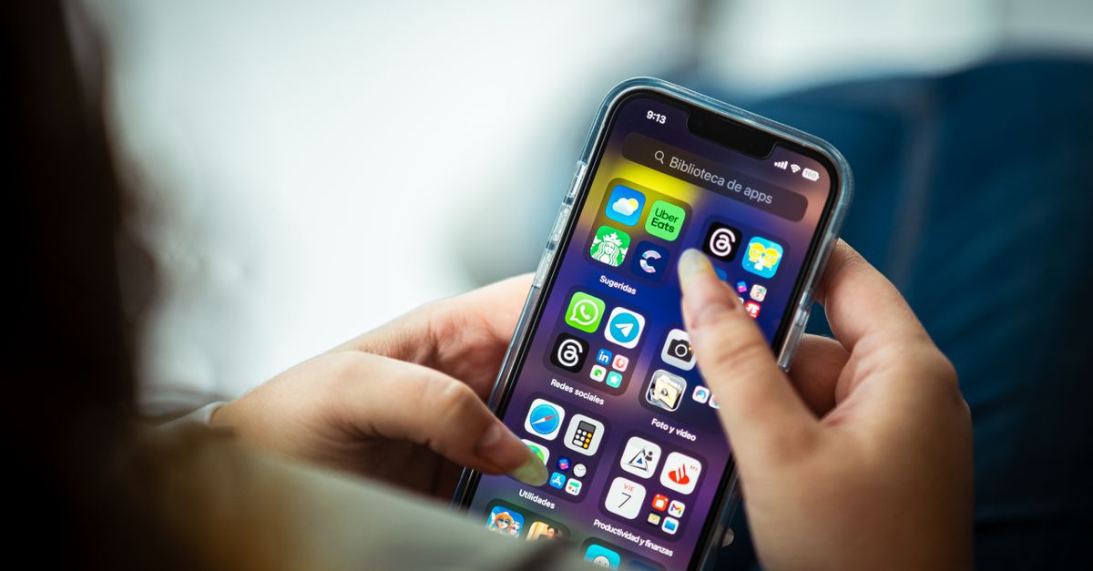 Close-up of a woman holding a smartphone displaying various apps.
