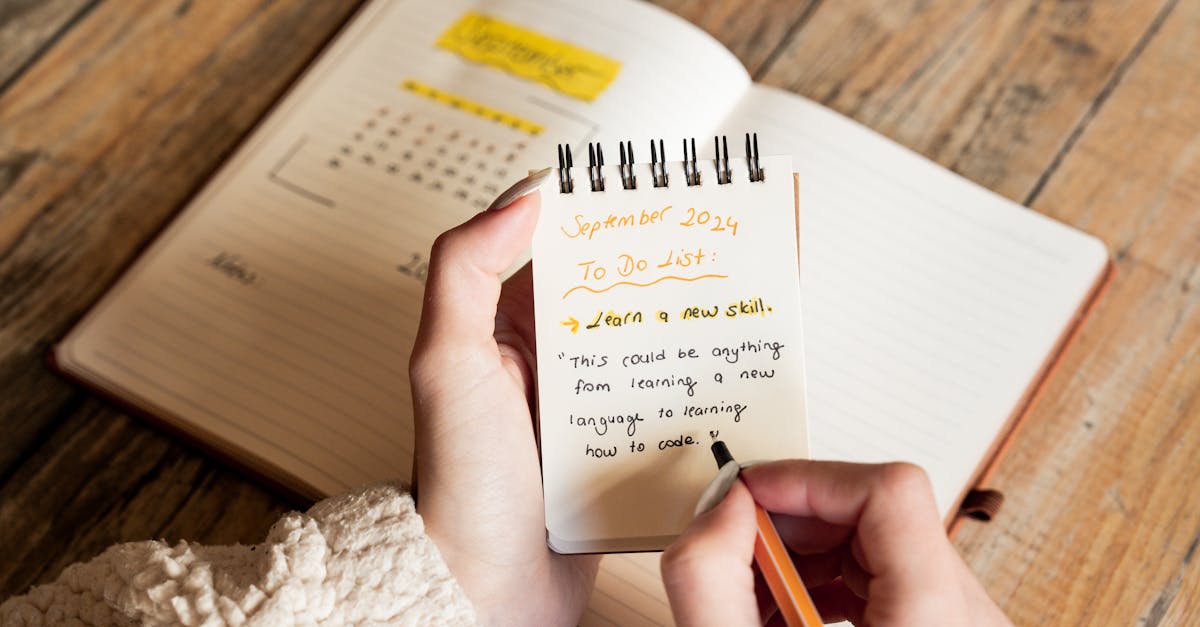 A person writes a September 2024 to-do list in a notebook, focusing on learning new skills.