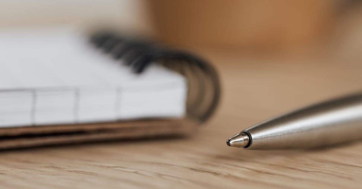 Side view closeup of opened ring bound notebook with blank pages near silver ball point pen placed on wooden t