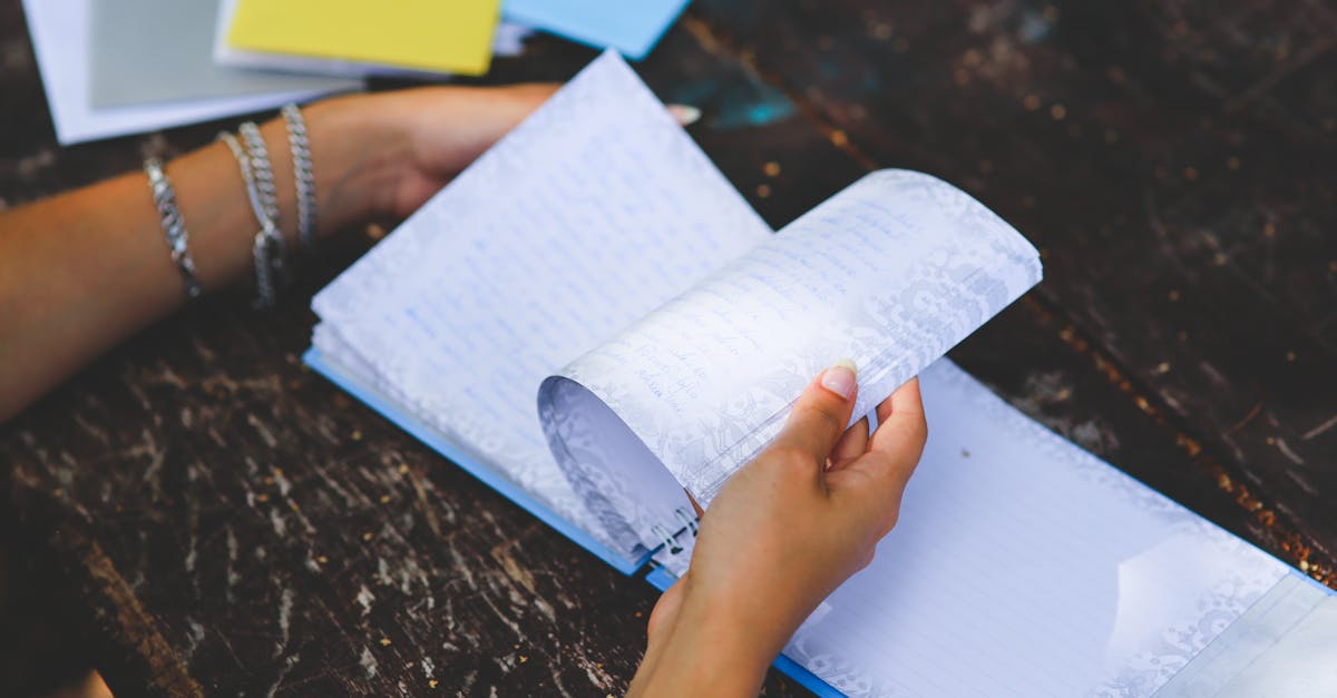 Close-up image of hands turning pages of a document on a desk indoors.