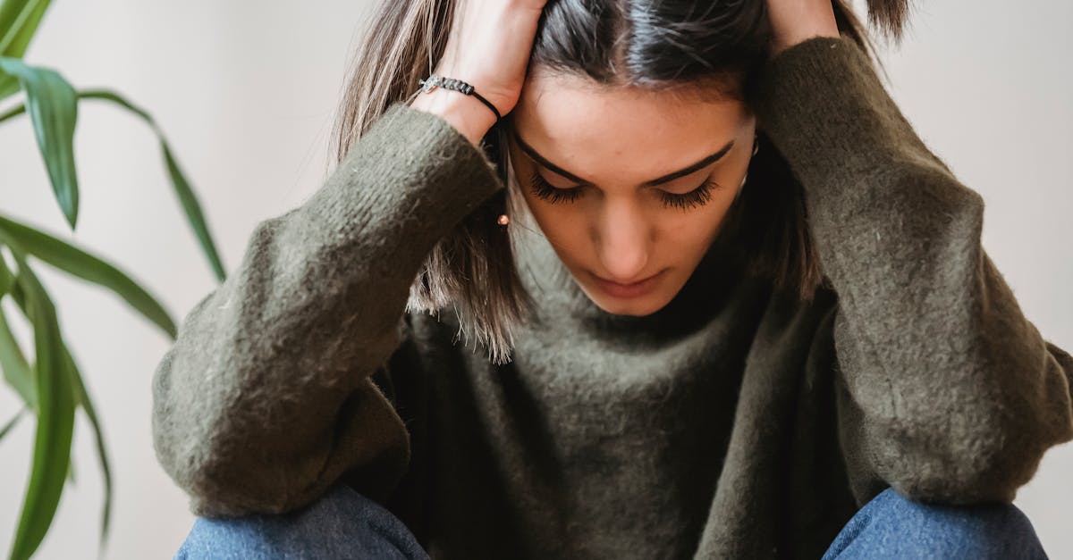 Crop disappointed young ethnic female with dark hair in casual clothes grabbing head with hands and looking do