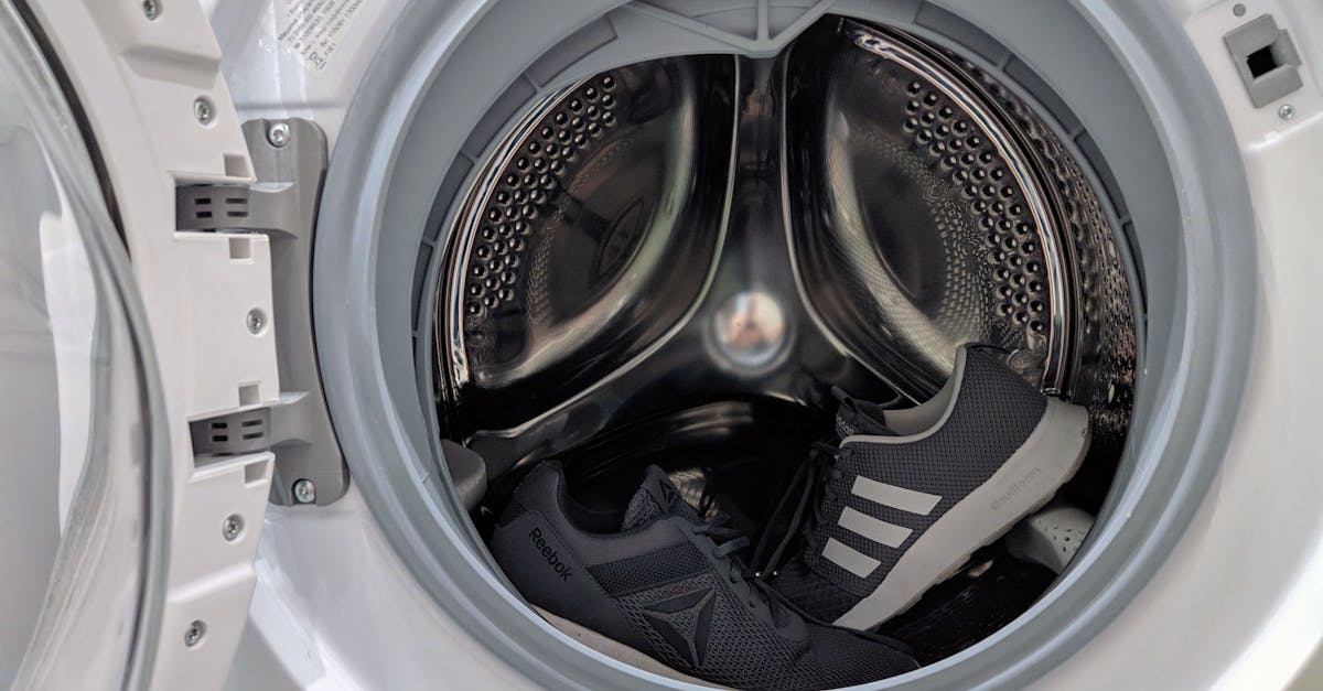 Close-up of black sneakers inside a washing machine drum showcasing laundry theme.