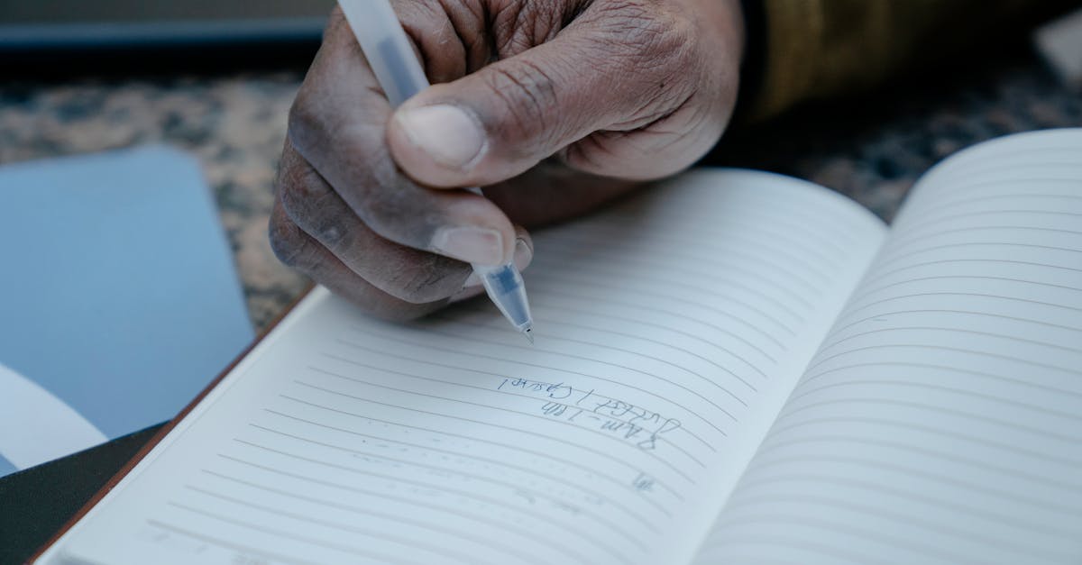 A close-up of a hand writing notes in a lined notebook with a pen.