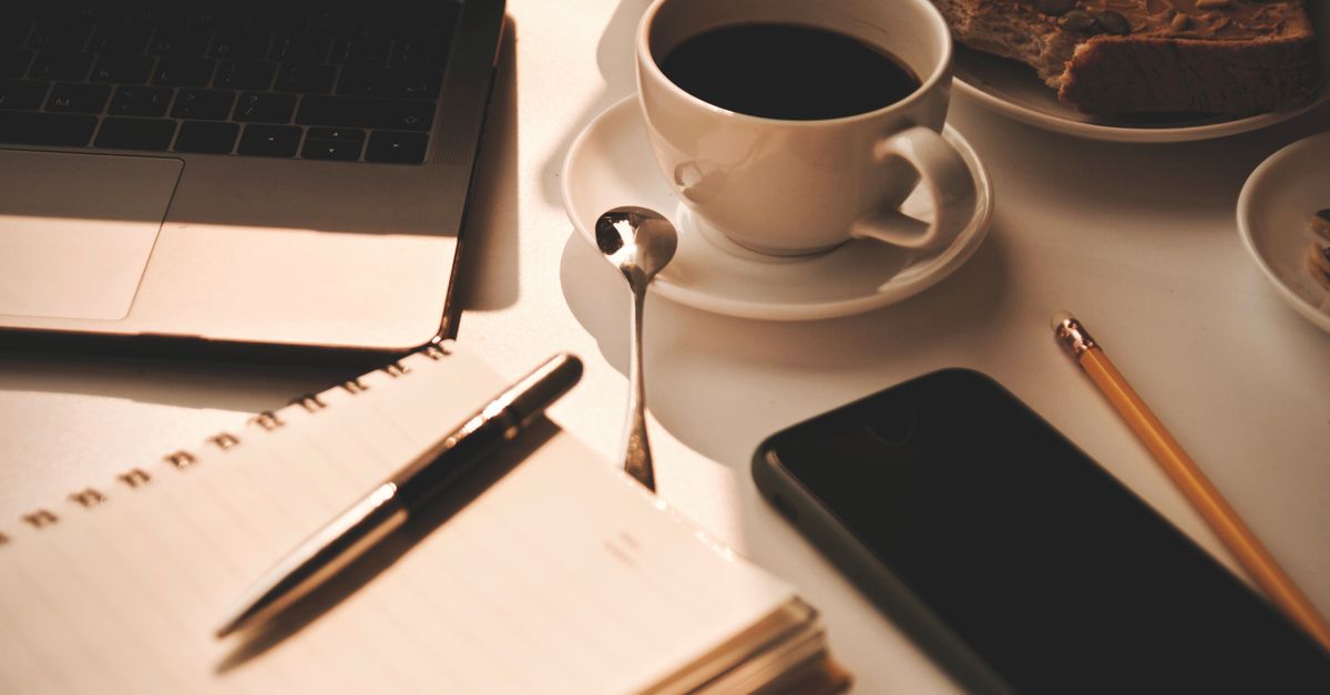 Warm and inviting workspace setup with coffee, notebook, and snacks, perfect for productivity.