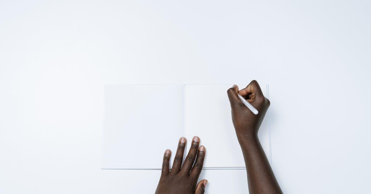 Top view of a person writing on a blank page in a notebook, showcasing simplicity and creativity.