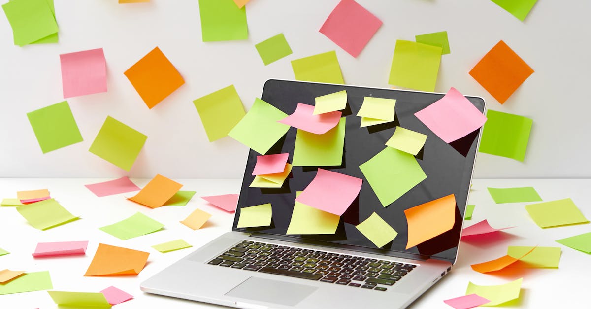 A laptop screen covered with vibrant sticky notes in a creative office setting.