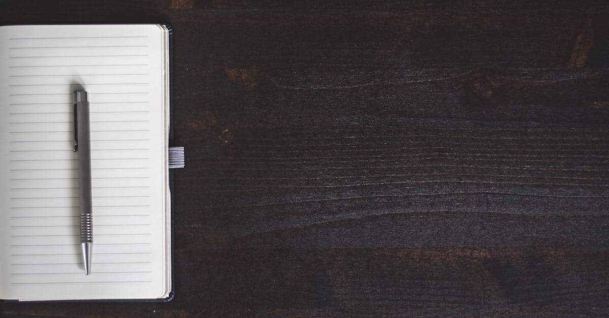 A minimalist open notebook with a pen on a dark wooden desk offering ample copyspace.