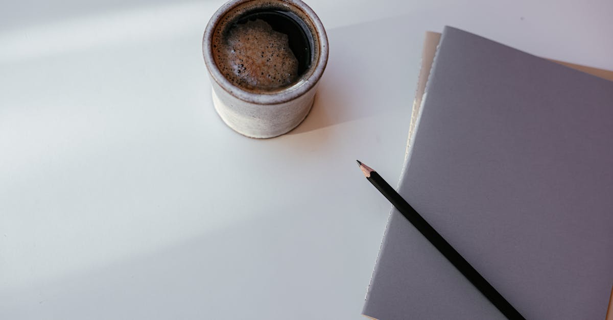 A cozy coffee mug with a notebook and pencil on a clean, minimalist desk.