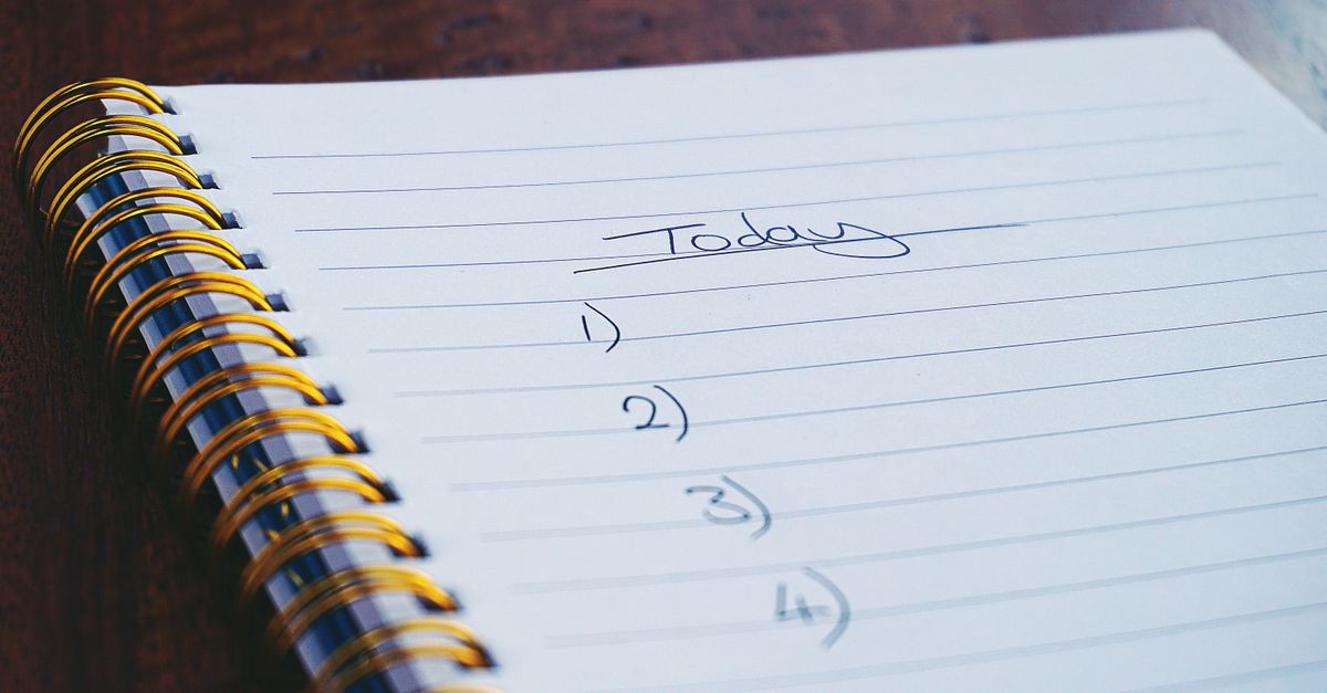 A close-up view of a handwritten to-do list on a spiral notebook with numbers for tasks.