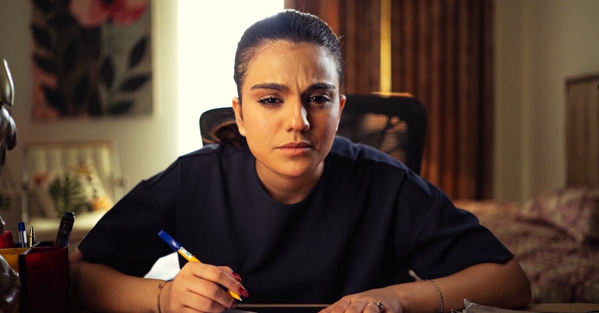 A woman intensely focused on writing notes at her home office desk, deep in concentration.