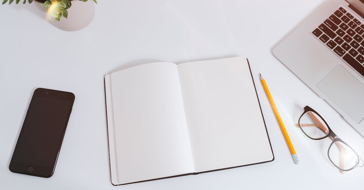 A simple workspace setup featuring a coffee cup, notebook, pen, and smartphone on a wooden desk.