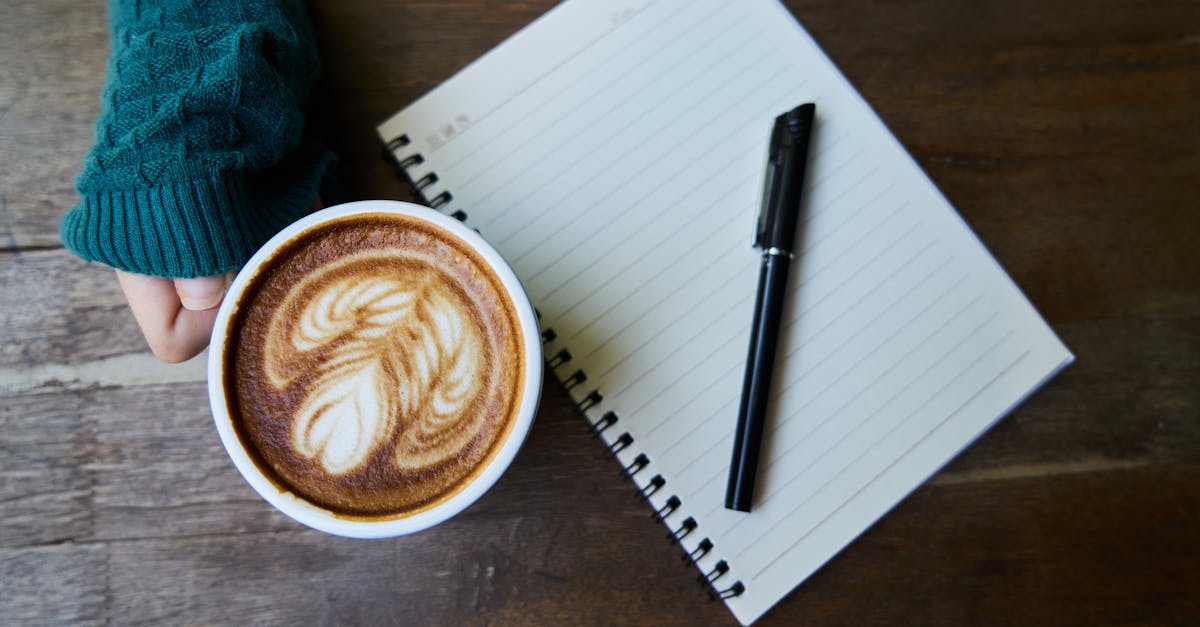 A cozy café scene featuring a latte with art, next to a notebook on a wooden table.