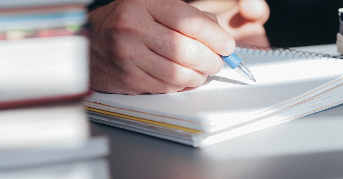A hand writing in a book by a window, bathed in warm natural light.