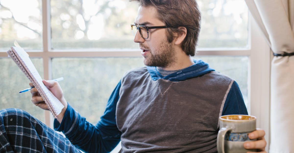 Casual man reading and studying indoors with a notebook and ceramic mug.