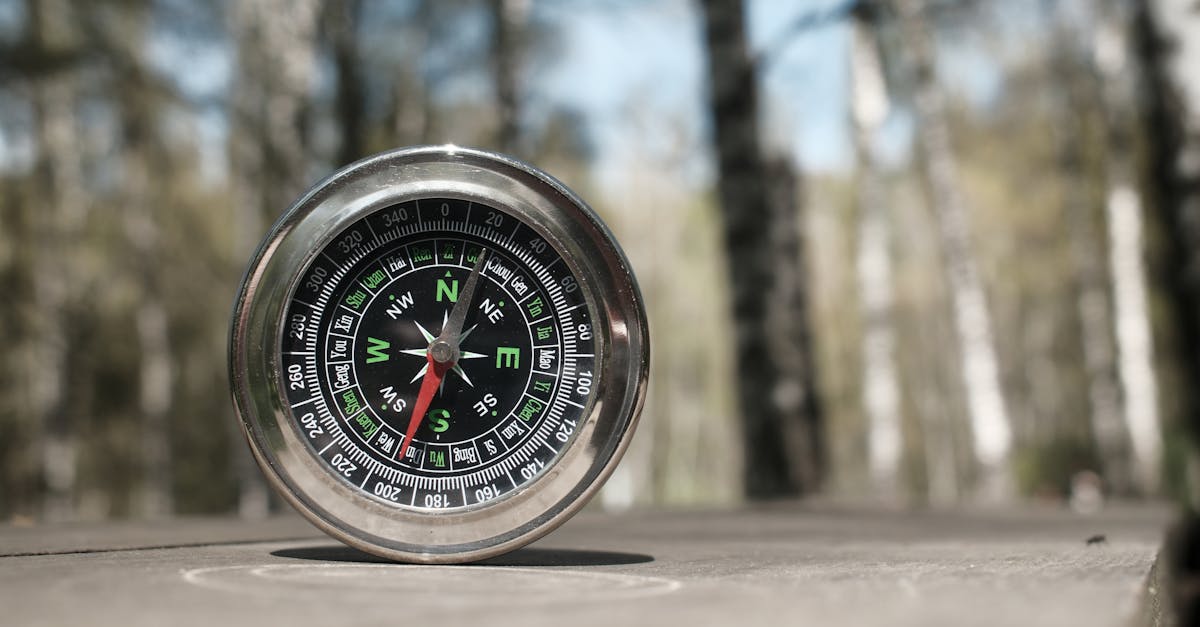 A compass resting on a wooden table in an outdoor forest setting, symbolizing navigation and exploration.