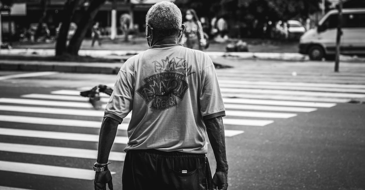 Black and white image of a man crossing a pedestrian lane in an urban setting.