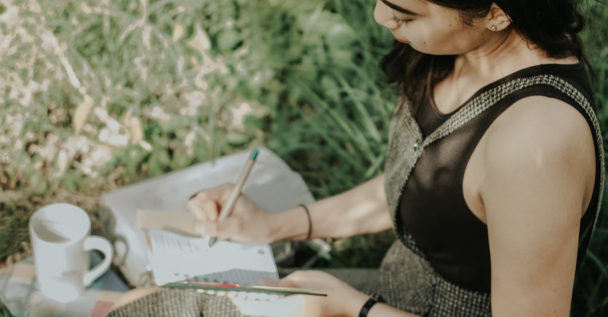 Young woman journaling outdoors, enjoying a peaceful moment with nature, pen in hand.