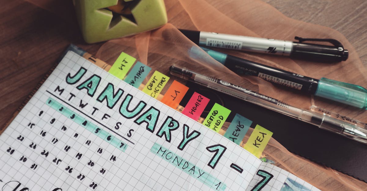 A detailed planner with goals and colorful tabs on a wooden desk with pens.
